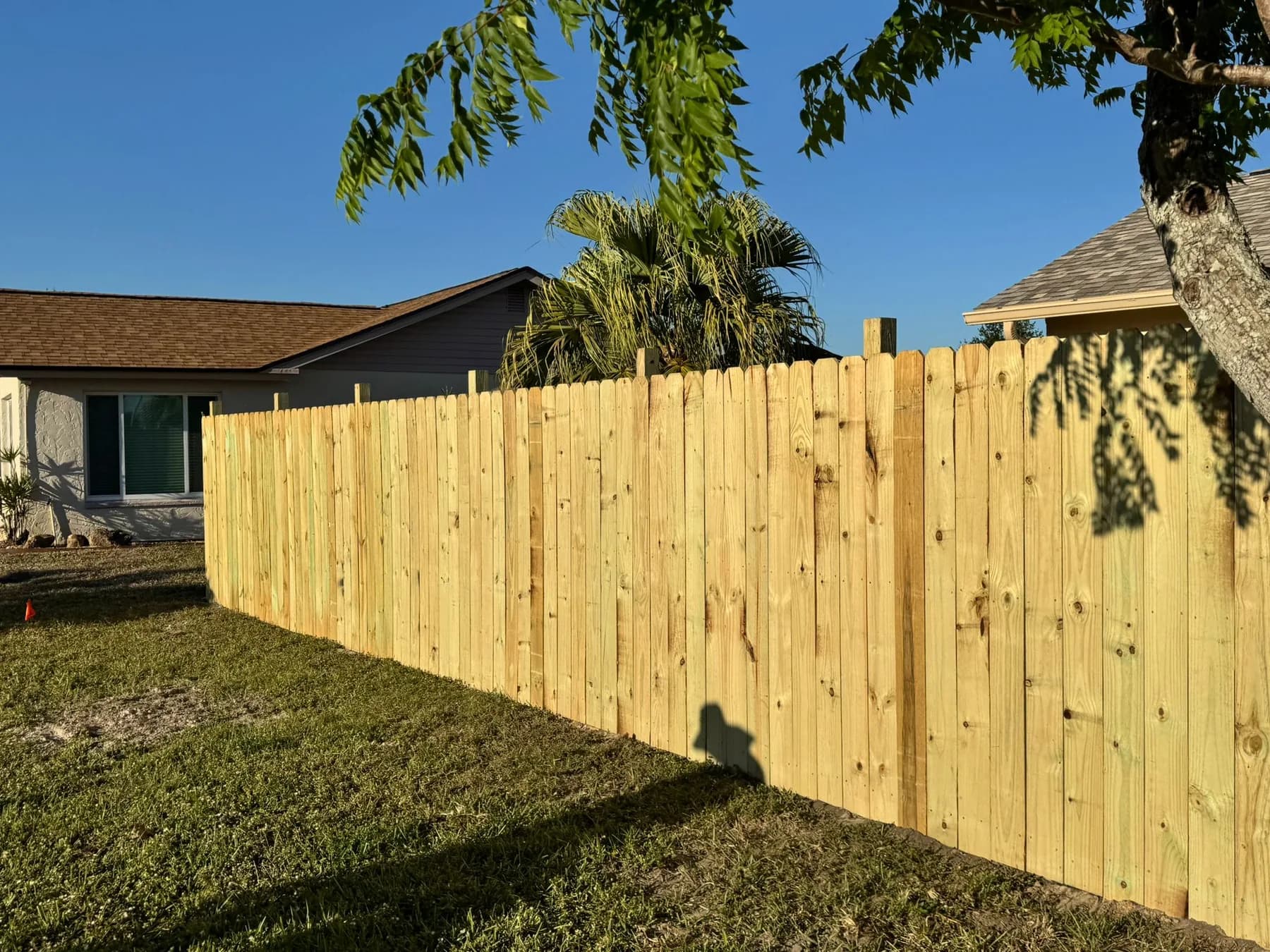 Fresh wood privacy fence installed with posts set in a residential yard